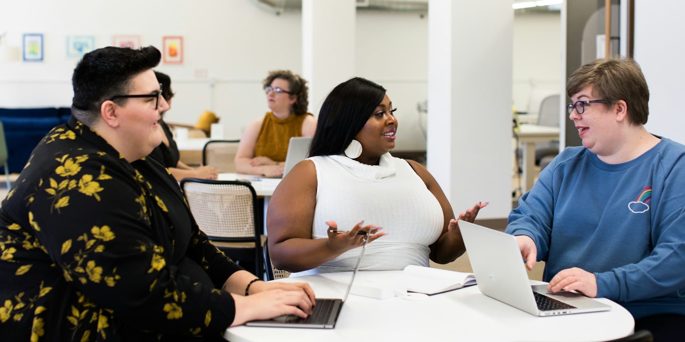 Three colleagues talking around a table in a bright office