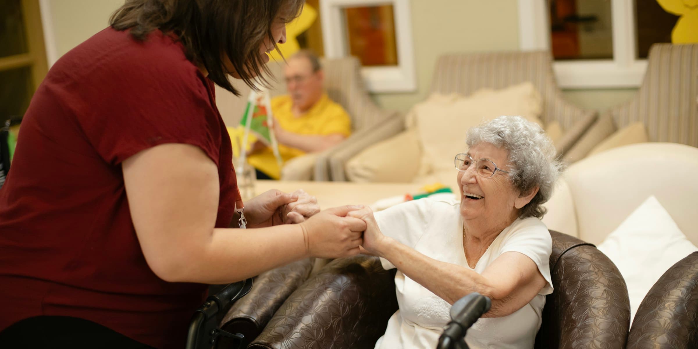 A Sahara Care aide holding hands with an older client in her living room