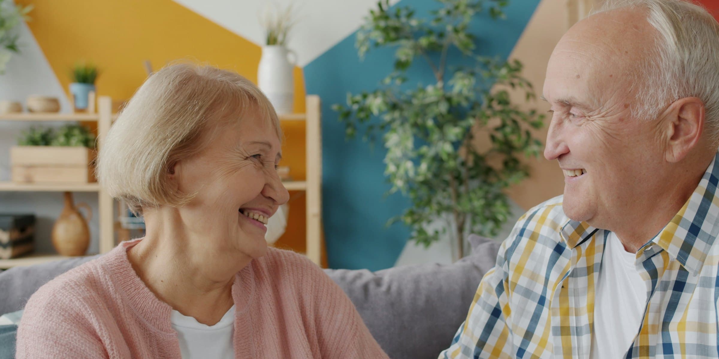 An older couple sitting together, smiling at each other