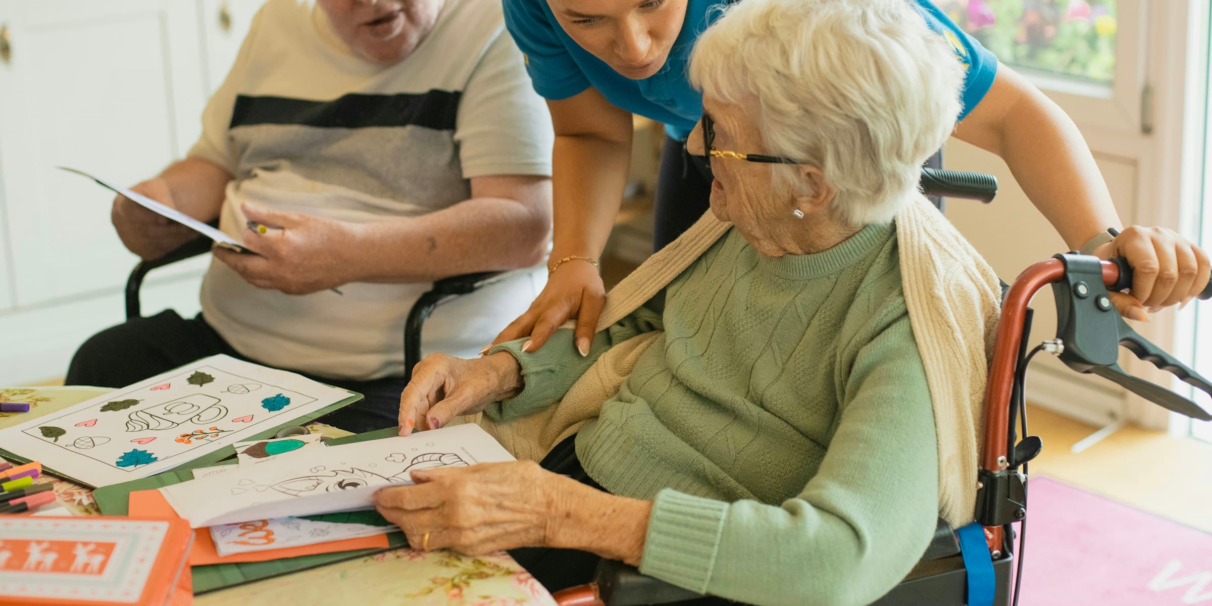 A caregiver supporting two clients at a table
